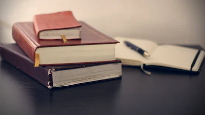 Trois livres à côté d'un cahier ouvert.